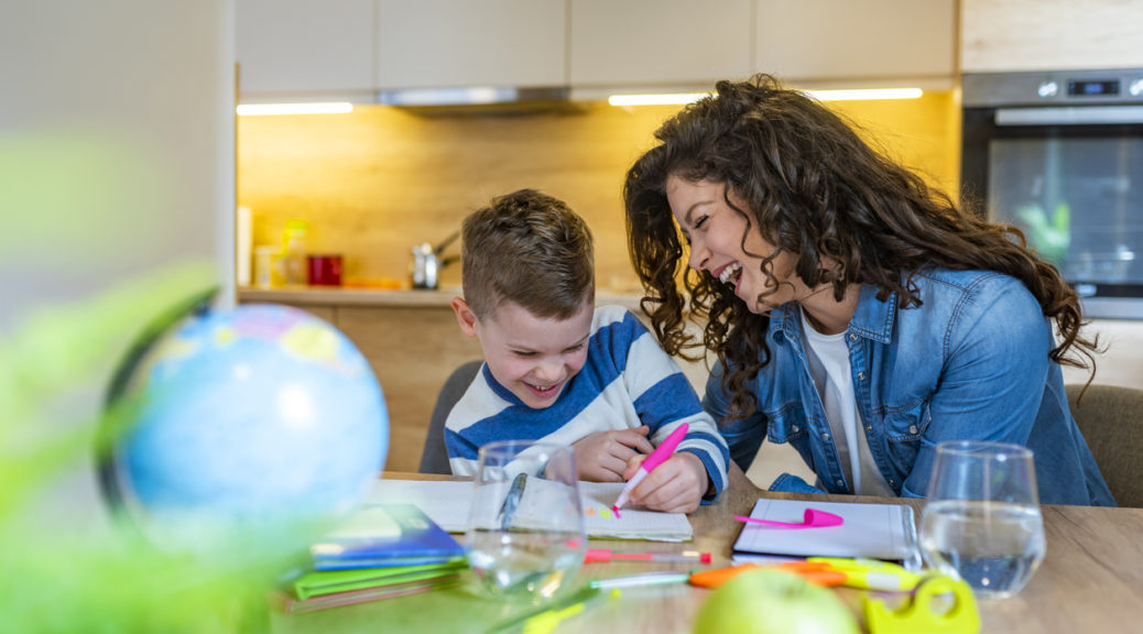 Mother and child laughing and drawing in the kitchen