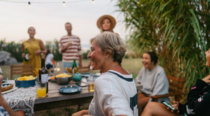 Photo of a woman enjoying the outdoor dinner party with her family and friends.