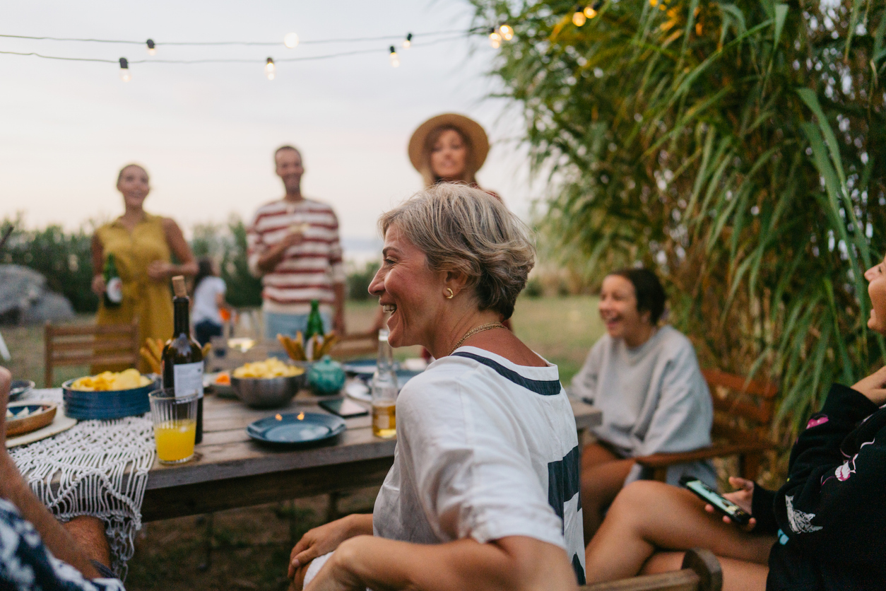 Photo of a woman enjoying the outdoor dinner party with her family and friends.