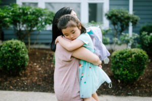 A Korean woman holds a girl tightly in an embrace, the girl feeling anxious.