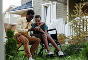 Full length portrait of smiling teenage boy looking at smartphone screen while spending time with father outdoors by house