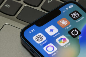 Assorted AI apps, including ChatGPT, Gemini, Claude, Perplexity, Meta AI, Microsoft Copilot, and Grok, are seen on the screen of an iPhone.