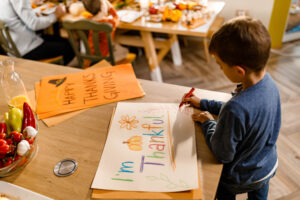 Small boy drawing a sign for Thanksgiving day at home.
