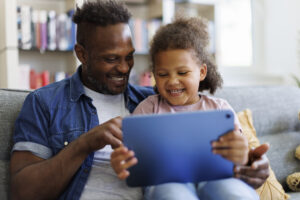 Father and daughter are having fun on a tablet at home