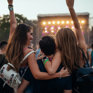 A family with a mom, brother and sister raising their arms while they enjoy a concert outside. Concerts are one of the most common gathering places of fandom.