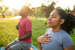Young couple practicing yoga in a summer park