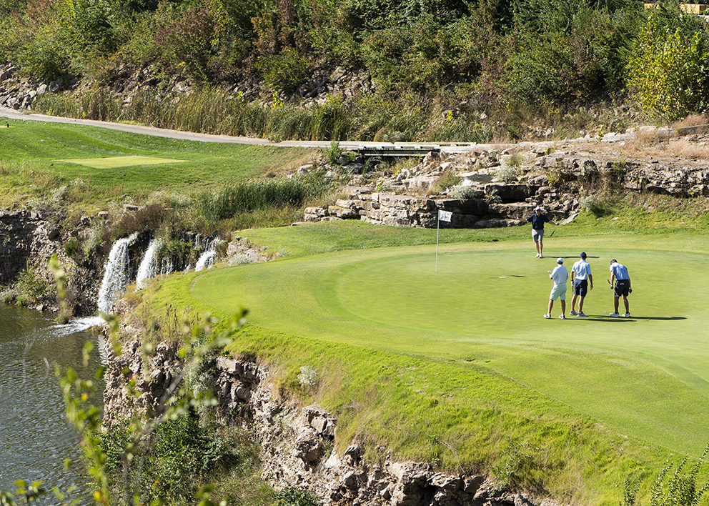 Golfers gather on a green beside a rocky waterfall at Canyon Farms Golf Club during the 2026 KVC Kids Classic.