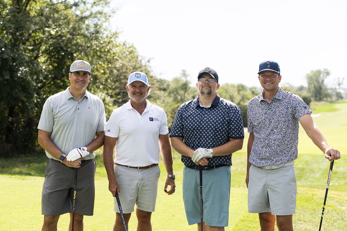 Four members of the Integrated Psychiatric Consultants golf team, third-place winners of the 2026 KVC Kids Classic, pose on the course.