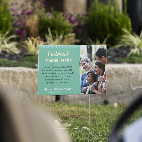 KVC Children's Mental Health sign displayed at the golf tournament highlights behavioral healthcare and psychiatric treatment for youth.